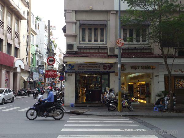 ドンコイ通り（Đồng Khởi）の両替所前、スクーターが走る交差点の風景（ホーチミン1区）