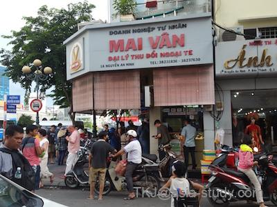 ベンタイン市場周辺の「Mai Văn（マイヴァン）」両替店前、混雑する交差点とバイクの列