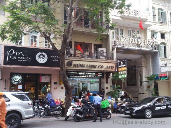 ホーチミン市1区ドンコイ通り（Đồng Khởi）の両替店「HUNG LONG CO., LTD」前の人だかりとバイク