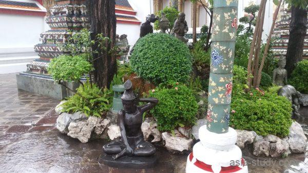 ワットポー境内の庭園、黒い像と花柄の柱（しっとり濡れた石畳）