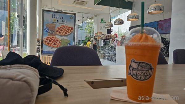 Café Amazon店内のテーブル、オレンジ色のスムージーが置かれた風景