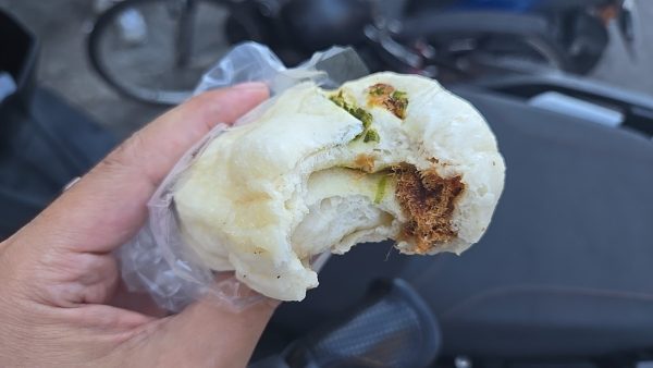 ねぎ入りのふわふわ蒸しパンをひと口かじった断面（バイクの前で手持ち）