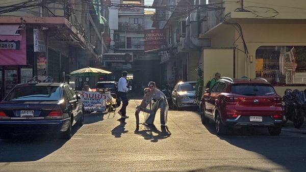 船着き場近くの路地、車の間でポーズする2人と夕方の逆光