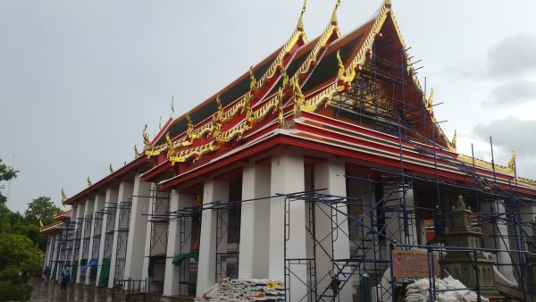 ワットポーの寺院建物（白い柱と赤金の屋根、修復中の足場が組まれた外観）