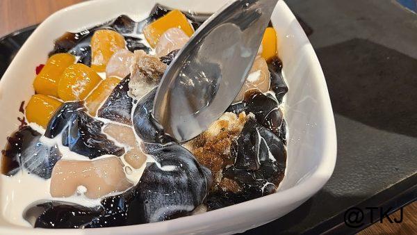 スプーンで混ぜた鮮芋仙のデザート、黒糖シロップとかき氷が見える