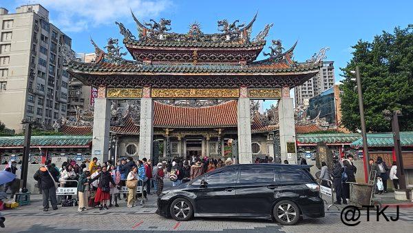 龍山寺の山門（正面）｜装飾が美しい門と、参拝客で賑わう入口の全景