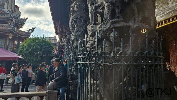 龍山寺の彫刻柱｜精密な石彫りの柱と、参拝客が行き交う境内の様子