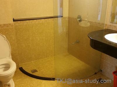 Quy Thanh Hotelのバスルーム。ガラス仕切りのシャワーと洗面台、トイレが並ぶ水回り