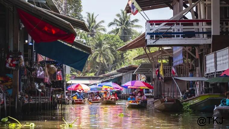 バンコクの水上マーケット、運河を進む小舟とカラフルな傘、両岸に並ぶ店の風景