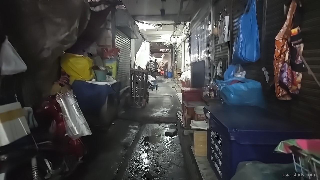 市場裏の細い路地、濡れた通路と雑多な荷物