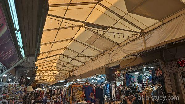 屋根付きの市場通路、天幕と衣料品の屋台が続く