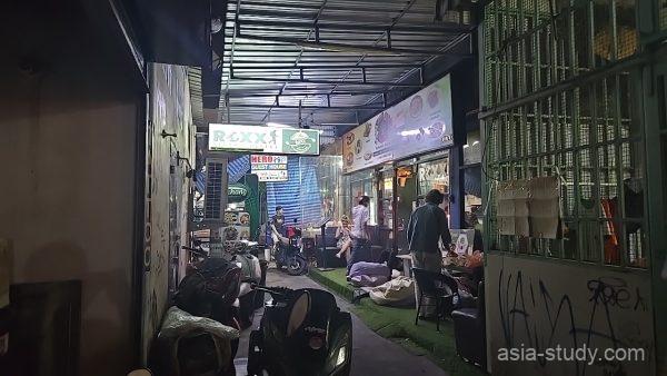 「ROXX SOCIAL HOSTEL」と「HERO」の看板が灯る、夜のゲストハウス街の奥行きある路地