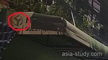 バンコク、カオサン通りのゲストハウスの看板をアップにし、赤線でロゴに丸をしている写真。薄暗い夜の雰囲気