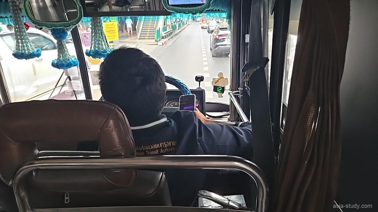 路線バス車内の後方から運転席方向、運転手のスマホと前方の車線が見える