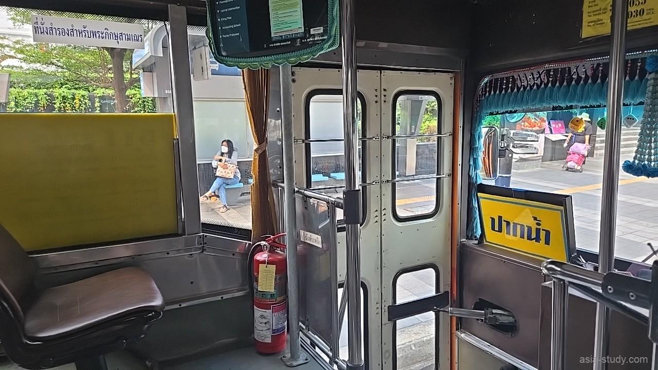路線バス車内の後部ドア付近、停留所で待つ人が窓越しに見える