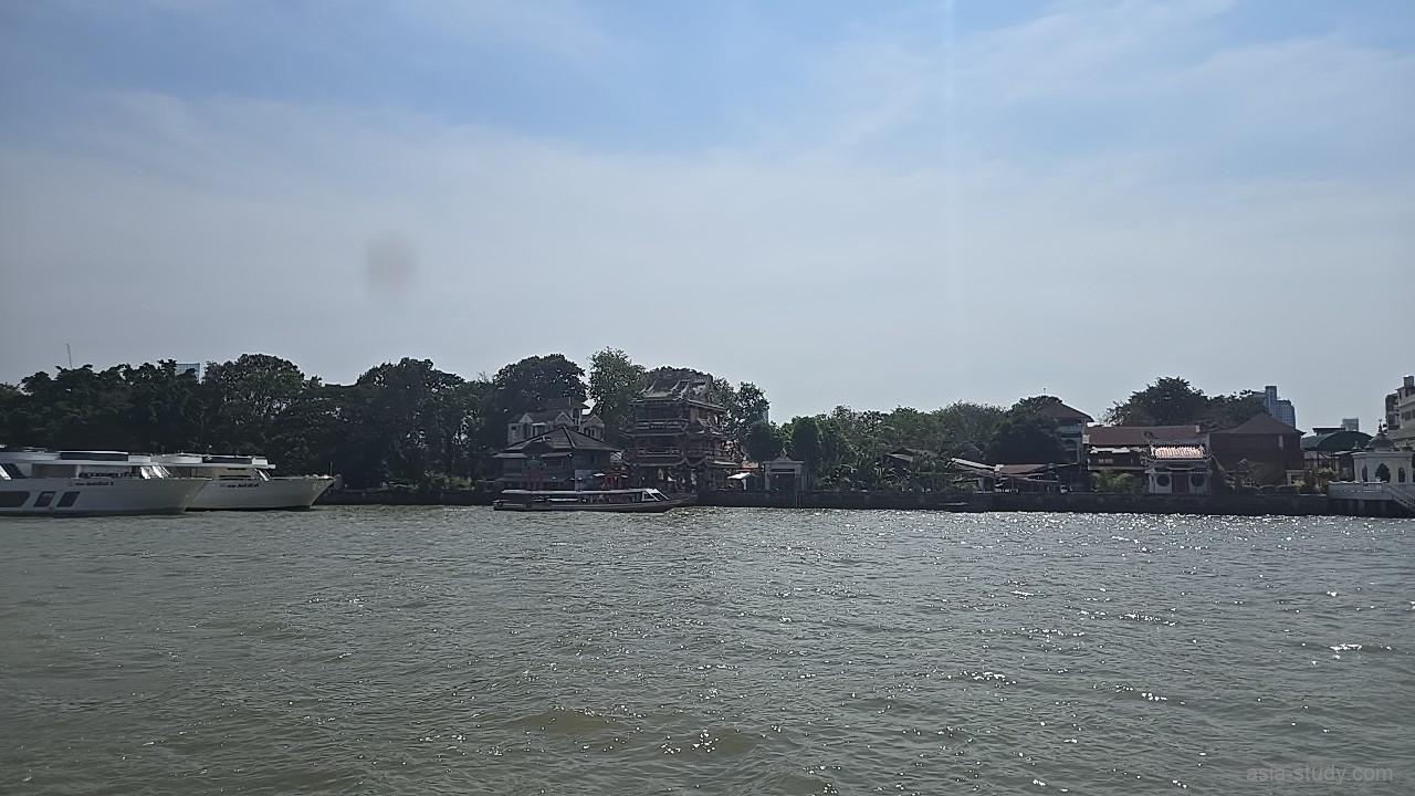 チャオプラヤー川を航行する船から望む、寺院や伝統的な建物が並ぶ情緒ある対岸の景色