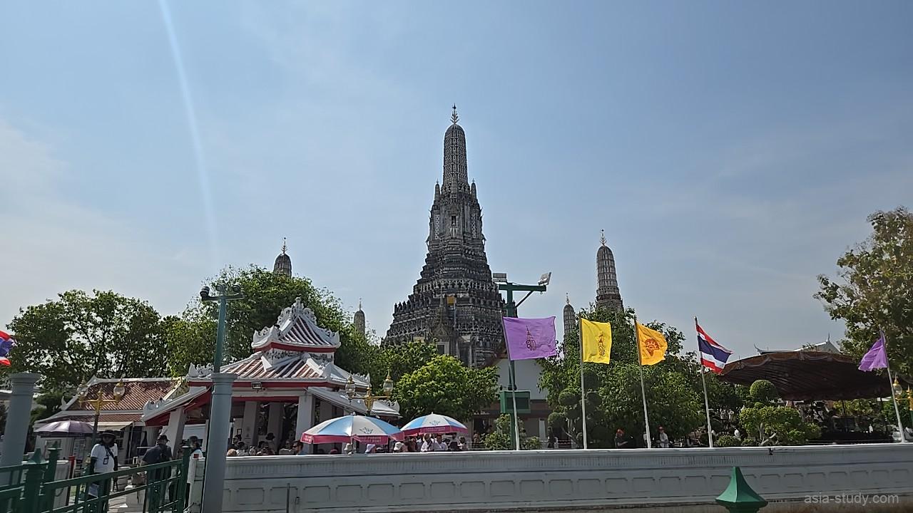 色とりどりの旗がはためく広場越しに望む、ワット・アルン（暁の寺）の巨大な大仏塔の全景
