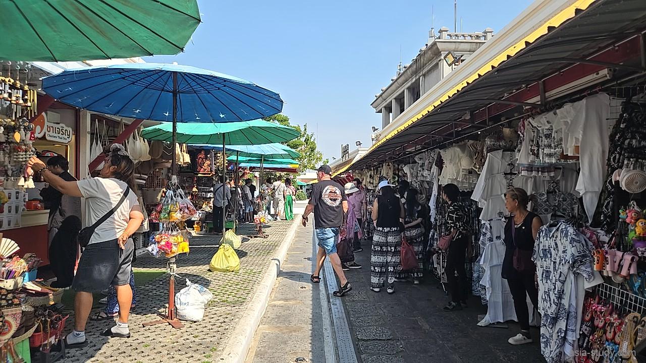 青いパラソルが並ぶ屋外の売店エリア。伝統的な装飾品や小物が販売されている