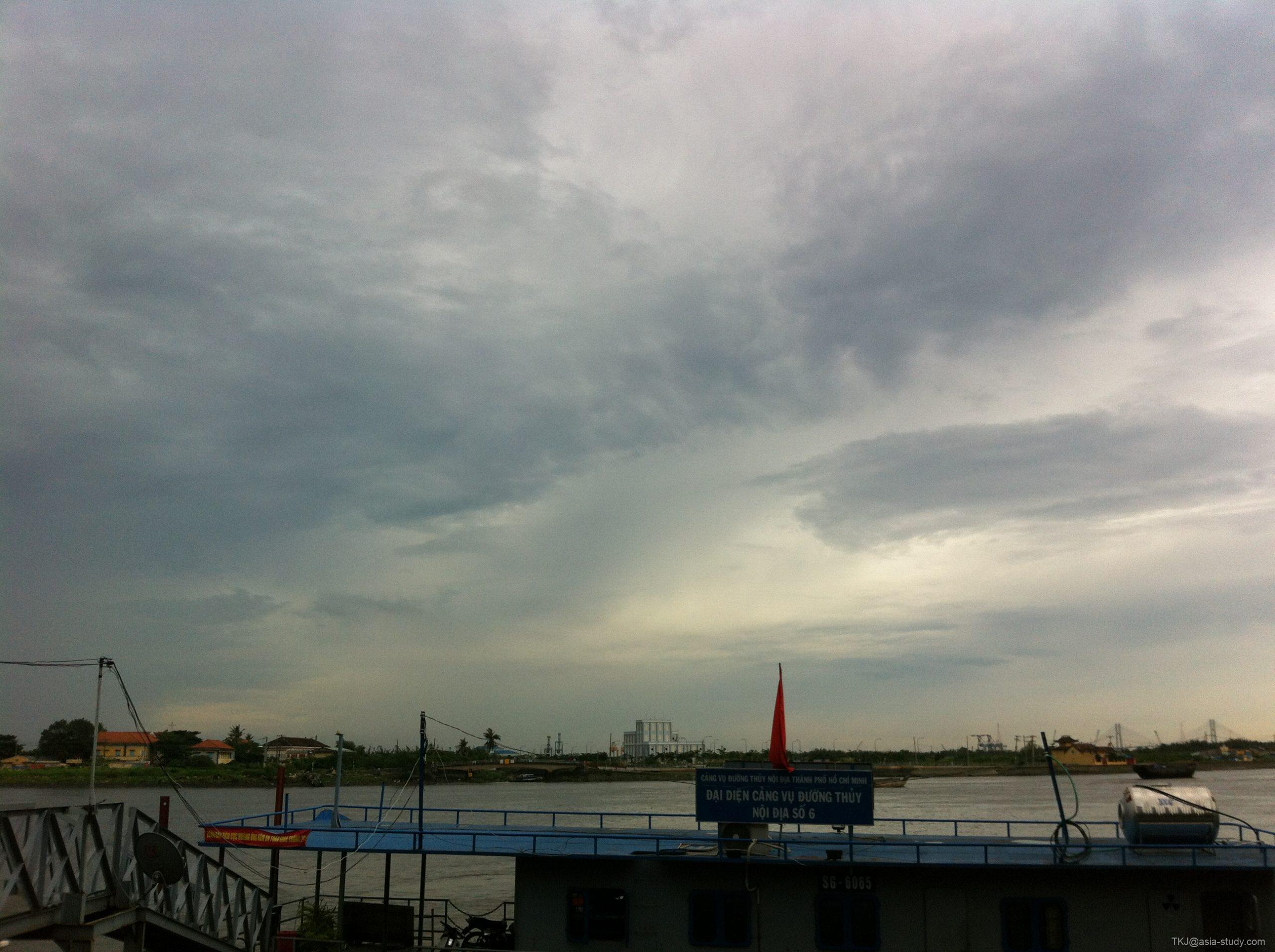 川沿いの景色と船、厚い雲が広がる空