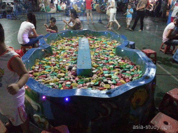ハントンタイ市場公園の夜店にある金魚すくい風ゲーム台（カラフルな玩具が水に浮かぶ）