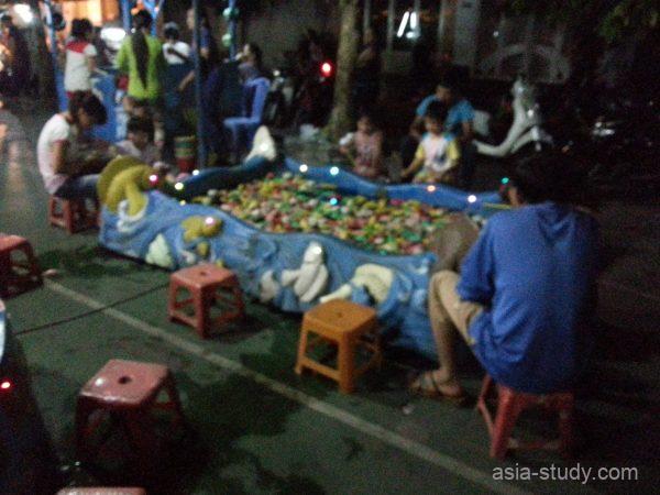 金魚すくい風のゲームコーナーを横から撮影（低いイスに座る人と子どもたち）