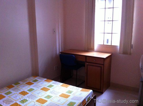 窓際に木製デスクと椅子が置かれたシンプルな個室（内見中）