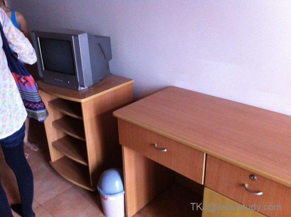 古いブラウン管テレビと木製棚、デスクが並ぶ部屋の家具