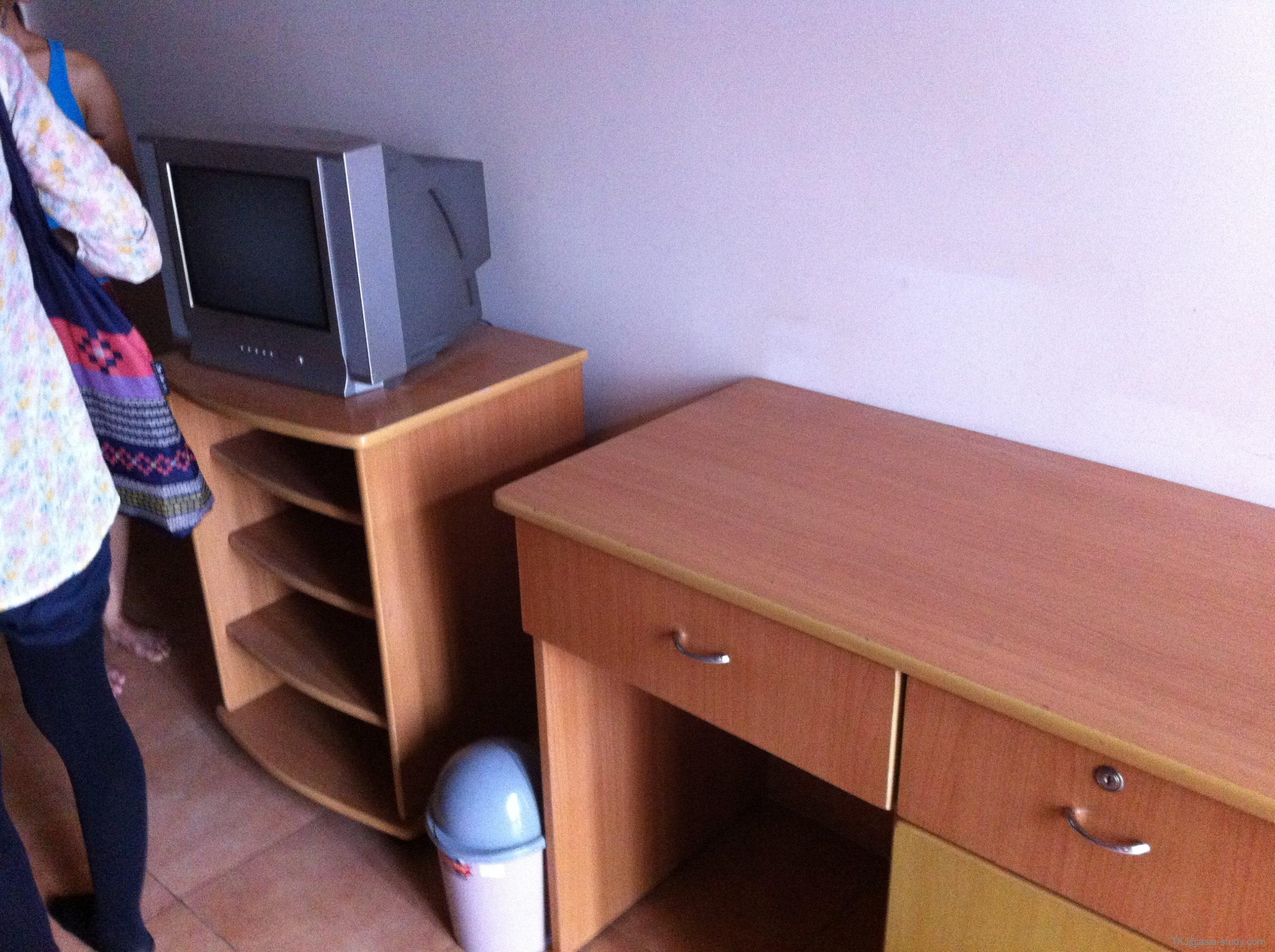 古いブラウン管テレビと木製棚、デスクが並ぶ部屋の家具