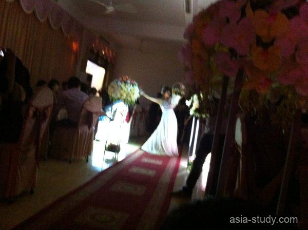 結婚式会場の通路でスポットライトを浴びるウェディングドレス姿の新婦