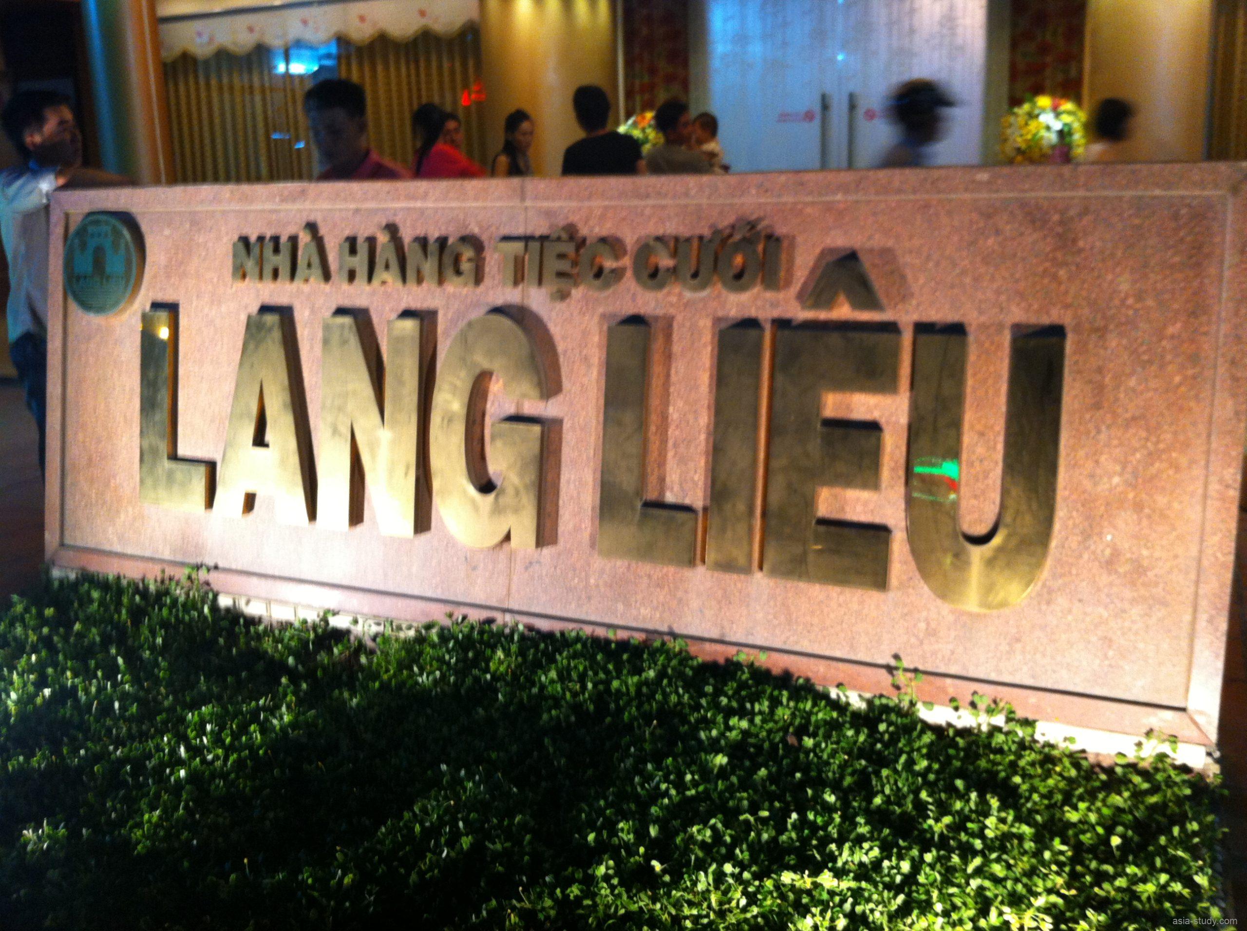 「NHÀ HÀNG TIỆC CƯỚI LÀNG LIỄU」と書かれた会場入口の看板（夜景）