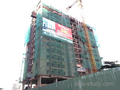 ホーチミン郊外（トゥードゥック周辺）の建設中の高層ビル、ネットで覆われた工事現場とクレーン