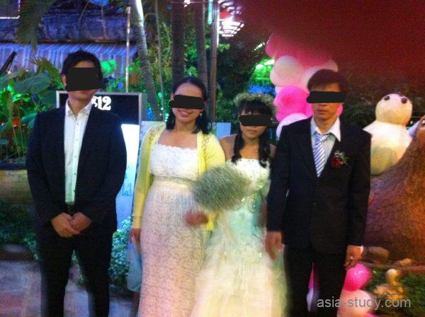 夜の屋外会場で新郎新婦とゲストが並んで記念撮影している様子