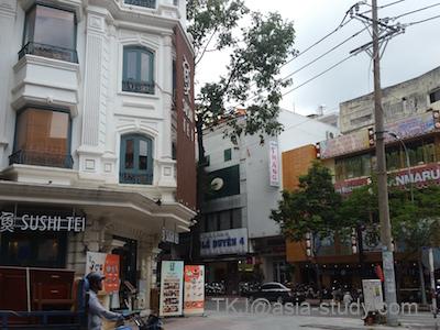 ホーチミン中心部の交差点と店舗が並ぶ街角。欧風建築とローカル店が混在する通り