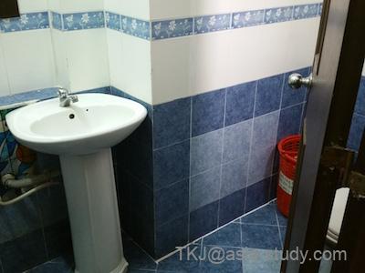 青いタイルのバスルーム。洗面台とトイレが並ぶシンプルな水回り