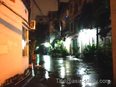 雨上がりの夜の路地。濡れた路面に街灯が反射するホーチミンの夜景