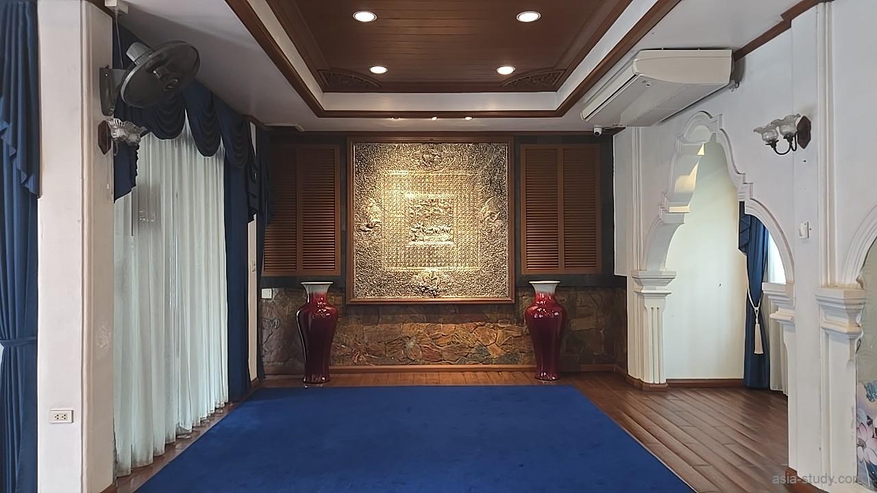 館内の金色レリーフパネルと赤い壺の装飾（白壁と木床の部屋）