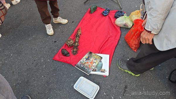 龍山寺横の路上フリーマーケットで赤い布の上に骨董品や本が並ぶ露店（台北）