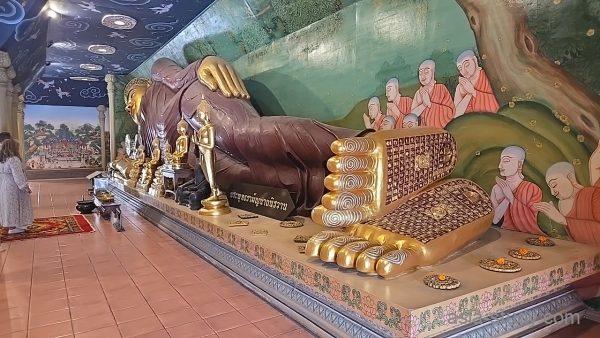 壁画の僧侶たちと並ぶ巨大な寝釈迦像（足裏の模様が目立つ）