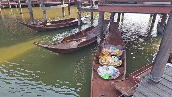 水辺に停泊する木船、船上に並ぶお菓子や土産物