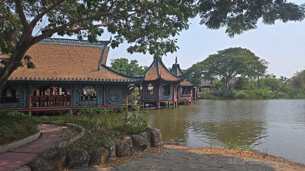 湖畔に建つオレンジ屋根の建物と水上のあずまや、静かな水面の風景