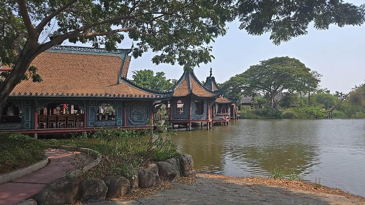 湖畔に建つオレンジ屋根の建物と水上のあずまや、静かな水面の風景