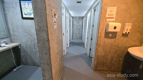 共用エリアの洗面台とシャワールーム前の通路、並ぶ個室ドア